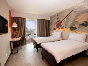 Una habitación de hotel con dos camas y un escritorio. en ibis Styles Lima Benavides Miraflores, en Lima