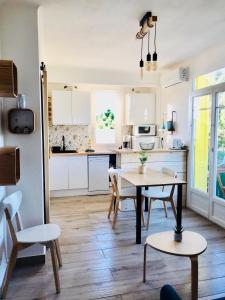 uma cozinha com armários brancos e uma mesa e cadeiras em Un petit nid les pieds dans l’eau em Argelès-sur-Mer