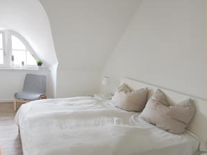 a white bed with white sheets and pillows at Haus Elve in Zierow