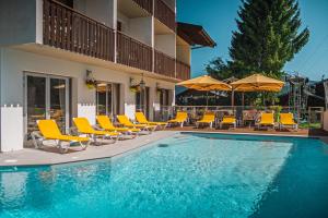a swimming pool with yellow chairs and umbrellas at Hôtel Le Christania in Bellevaux