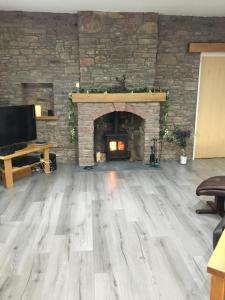 uma sala de estar com uma lareira de pedra e pisos de madeira em Ben Lomond Cottage em Gartocharn