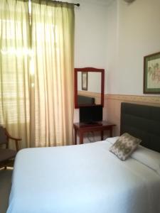 ヘレス・デ・ラ・フロンテーラにあるヌエボ ホテルのベッドルーム(鏡付き白いベッド1台、デスク付)