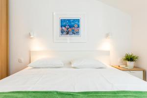a bedroom with a white bed with a green blanket at Jadrija Bay in Šibenik