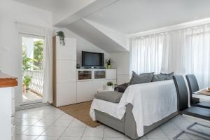 a white bedroom with a bed and a tv at Jadrija Bay in Šibenik