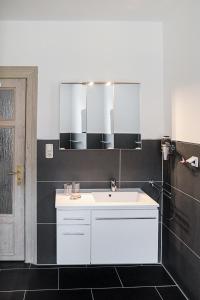 ein Badezimmer mit einem weißen Waschbecken und einem Spiegel in der Unterkunft Appartement Schloßstraße in Ballenstedt