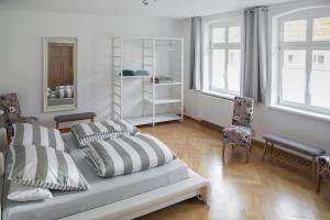 ein weißes Schlafzimmer mit einem Bett und einem Stuhl in der Unterkunft Appartement Schloßstraße in Ballenstedt