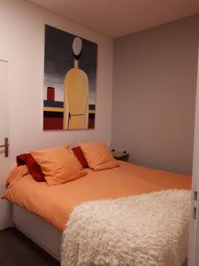 um quarto com uma cama com almofadas laranja e um quadro em galerie Angle3 em Quimper