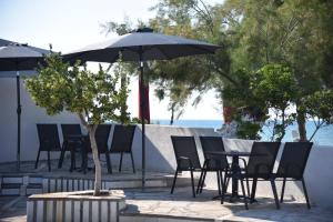 a group of chairs and tables with an umbrella at Family apartments 1 in Lékhaion