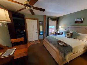 um quarto com uma cama, uma secretária e uma ventoinha de tecto em The Barn Inn Bed and Breakfast em Millersburg