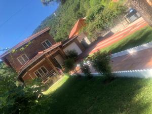 una casa en una colina con un patio verde en CHALET EN EL CORAZÓN DE LA SIERRA DE GREDOS, PINAR DE LA ATALAYA-TIEMBLO, en El Tiemblo