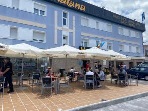 people sitting at tables under umbrellas in front of a building at H Viella Asturias in Viella