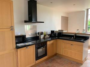 a kitchen with wooden cabinets and black counter tops at LA PETITE ECOLE in Chambellay