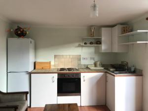 a kitchen with white cabinets and a white refrigerator at cosy cottage annex in Fairlop in Ilford