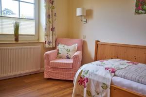 a bedroom with a bed and a chair and a window at Flair Landhotel Strengliner Mühle in Pronstorf