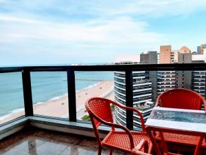 Duas cadeiras e uma mesa numa varanda com praia em Hotel Flat Atlântico em Fortaleza