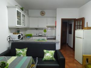 een keuken met een zwarte bank en een witte koelkast bij Casa de Praia da Lú in Figueira da Foz