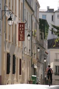 a man riding a bike down a city street at Hôtel du Roussillon in Paris