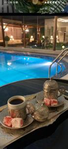 a plate of food and a cup of coffee next to a pool at Alreem challet in Abha