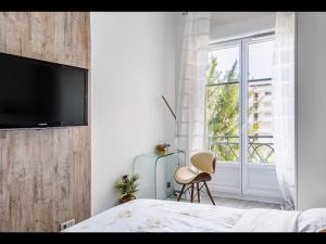 - une chambre avec un lit et une télévision murale dans l'établissement La Croisette - Superbe studio au mythique Palais Miramar, à Cannes