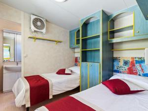 dwa łóżka w sypialni z niebieskimi szafkami i łazienką w obiekcie Mobile Home in Banjole near Beach Centinera w mieście Banjole