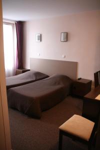 a hotel room with two beds and a window at Hôtel du Roussillon in Paris