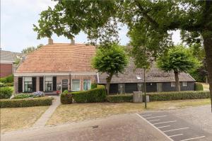 a house with a red roof on a street at De Lindehoeve Appartement de Deel in Vledder