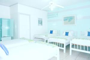 Habitación blanca con 3 camas y ventilador de techo. en Hotel Ivania´s, en Masaya