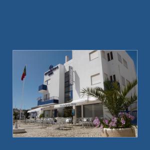 a white building with tables and chairs in front of it at RESIDENCIAL RITA in Odemira