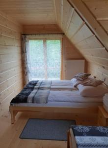 a bed in a wooden room with a window at Domek Góralski Limba 1 in Kościelisko
