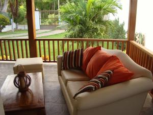 kanapa z poduszkami na werandzie ze stołem w obiekcie Cozy Cottage Posada Turistica w mieście San Andrés