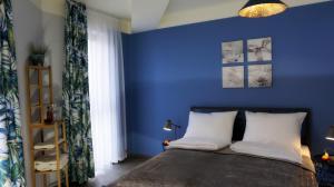 a bedroom with blue walls and a bed with white pillows at Fajny Kąt - Apartamenty w centrum, najwyższe opinie gości in Jelenia Góra
