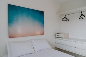 a white bedroom with a bed and a painting on the wall at Jardim das Palmeiras II - Multipropriedade in Ubatuba +77 photos