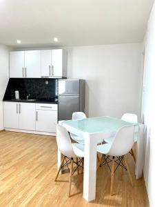 a kitchen with a table and white chairs at Apartmani GO Bugojno in Bugojno