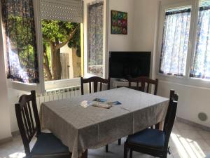 una sala da pranzo con tavolo, sedie e finestre di Appartamento Marina a Finale Ligure