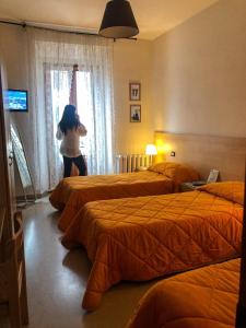 カスティリオーネ・デイ・ペーポリにあるアルベルゴ リストランテ ラ トレッタのベッド3台付きのホテルルームに立つ女性