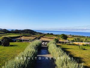 un camino a través de un campo con el océano en el fondo en Basalto Negro AL, en Angra do Heroísmo