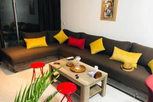 Una sala de estar con un sofá con almohadas amarillas y rojas. en Pieds dans l'eau, piscine face à la mer - Adan beach - entre Agadir et Taghazout, en Agadir