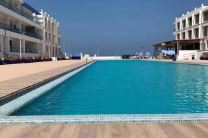 Una piscina con agua azul frente a un edificio. en Pieds dans l'eau, piscine face à la mer - Adan beach - entre Agadir et Taghazout, en Agadir