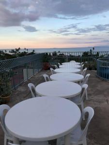una fila de mesas y sillas blancas con el océano en el fondo en Bulusan Tourist Inn, en Bulusan