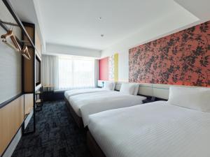 a row of beds in a hotel room at Mitsui Garden Hotel Kyoto Shijo in Kyoto