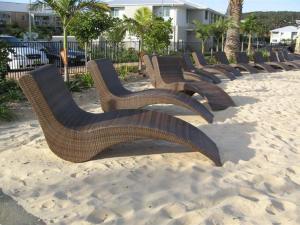 a row of wooden benches sitting in the sand at Oaks Pacific Blue 339 Huge Resort Lagoon Pool in Salamander Bay