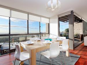 a dining room with a table and chairs and large windows at One Mile Ridge stunning views air con infinity pool in Anna Bay