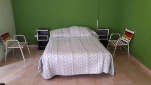 a bed in a room with chairs and a green wall at Complejo Berazategui in Villa D. Sobral