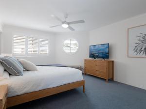 um quarto com uma cama e uma ventoinha de tecto em Pelican Sands 3 stunning waterfront unit with magical water views and air conditioning em Soldiers Point