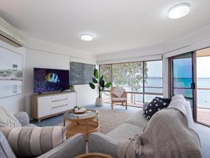 a living room with a couch and a tv at Pelican Sands 3 stunning waterfront unit with magical water views and air conditioning in Soldiers Point