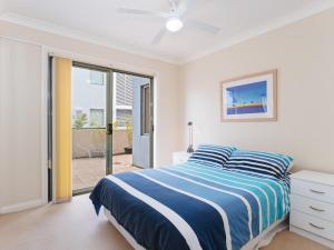 a white bedroom with a bed and a sliding glass door at Peninsula Waters 2 three bedroom unit with spacious private courtyard and WI-FI in Soldiers Point