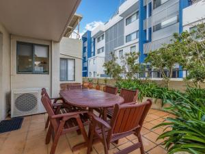 a patio with a wooden table and chairs at Peninsula Waters 3 Beautiful Air Conditioned Unit with Pool Lift and WI-FI in Soldiers Point