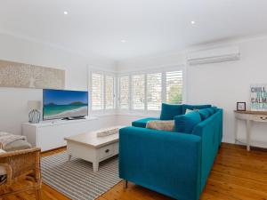 un salon avec un canapé bleu et une télévision dans l'établissement Rubys Retreat, 44 Achilles Street - pet friendly, aircon, wifi & boat parking, à Shoal Bay