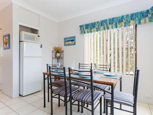eine Küche mit einem Tisch und Stühlen sowie einem Kühlschrank in der Unterkunft Sailfish, 4,46 Magnus Street- Unit with water views and close to town in Nelson Bay