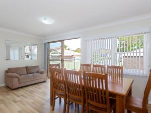 a dining room with a table and chairs and a couch at Sandy Shoal Shoal Bay Beach Cottage with aircon in Shoal Bay